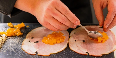 Выложите на&nbsp;ломтики окорока измельчённую хурму и&nbsp;сыр